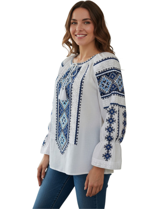 Woman wearing a white blouse with blue embroidery on a white background