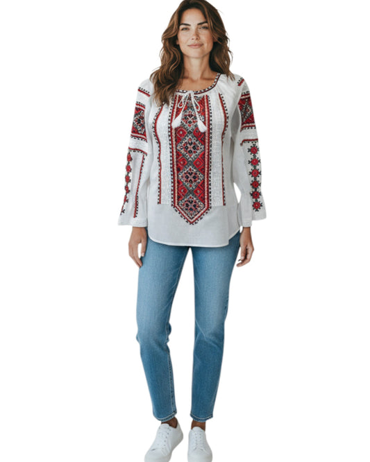 Woman wearing a white blouse with red and black embroidery and blue jeans on a white background