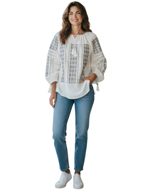 Woman wearing a white embroidered blouse and blue jeans on a white background