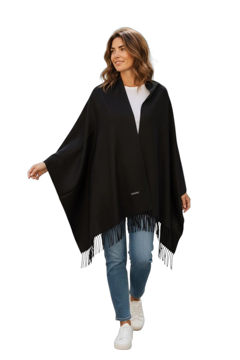 Woman wearing a black poncho with fringe on a white background